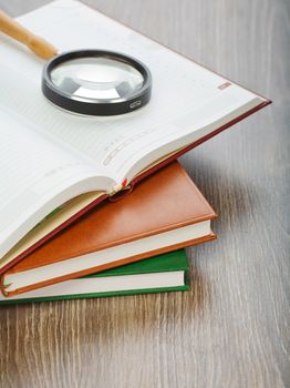 diaries and magnifier on wooden background