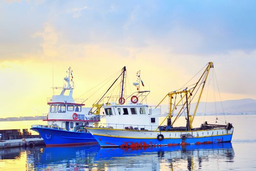 fishing boats under a sunset in a fishing harbor