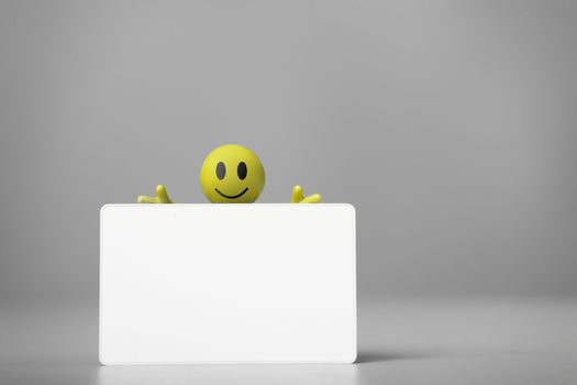 Yellow man in overalls holding a blank business card. on a gray background