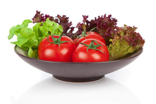 tomatoes and green salad in the bowl, over white background