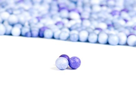 One blue and two violet little pearls isolated on background of other pearls.