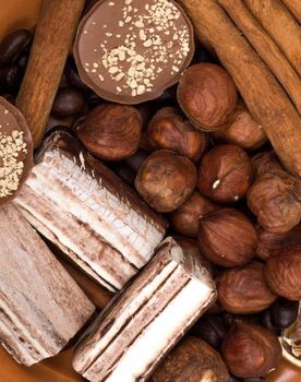 Sweets, cinnamon, nuts and coffee beans on a saucer, on burlap background.