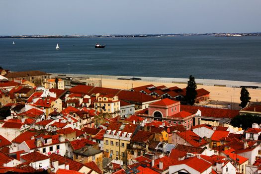 Panorama of ancient city of Lisbon with red roofs, river, ship