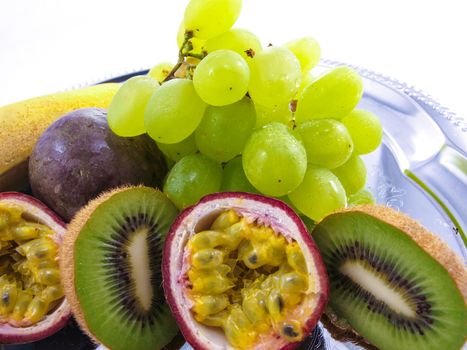 Assorted fruits, isolated on a silver plate, towards white background