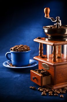 composition of grinder and cup on a plate with coffee grain