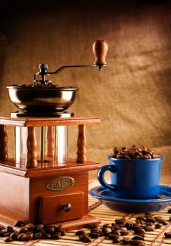 compositioon of grinder and coffee grains and blue mug