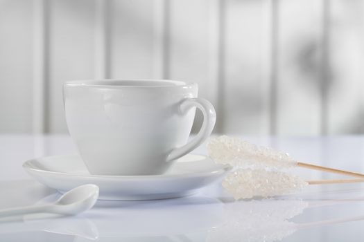 a coffee cup with spoon and sugar stick on white table 