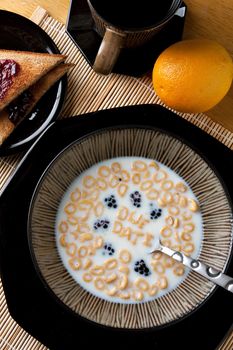 The words DUE DATE spelled out of letter shaped cereal pieces floating in a milk filled cereal bowl.