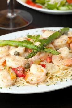 A delicious shrimp scampi pasta dish with antipasto salad in the background.