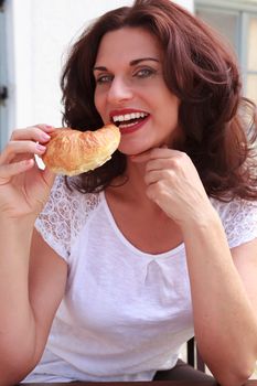Attractive businesswoman eating a croissant at