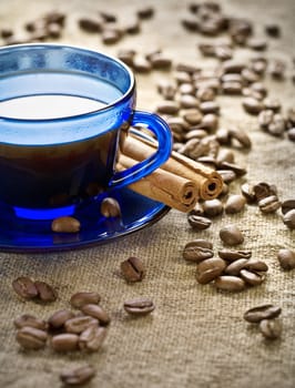 cinnamon and coffee beans with cup on saucer