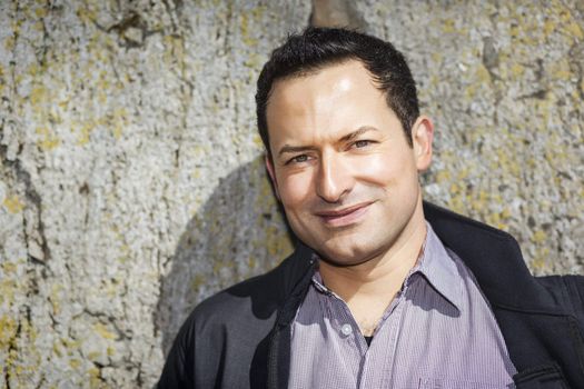 A man in front of a natural stone wall