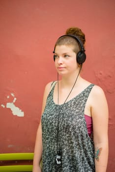 beautiful stylish modern young woman listening to music in the city