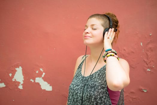 beautiful stylish modern young woman listening to music in the city
