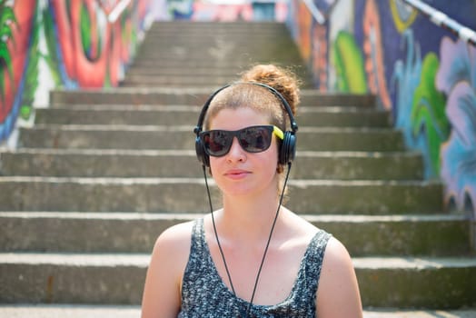 beautiful stylish modern young woman listening to music in the city