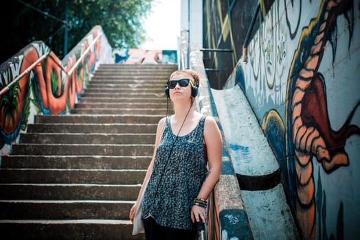 beautiful stylish modern young woman listening to music in the city