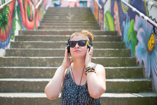 beautiful stylish modern young woman listening to music in the city