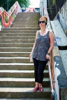 beautiful stylish modern young woman listening to music in the city