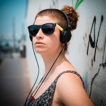 beautiful stylish modern young woman listening to music in the city