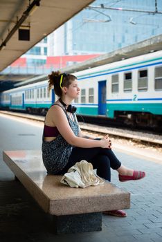 beautiful stylish modern young woman waiting train at the station