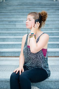 beautiful stylish modern young woman listening to music in the city