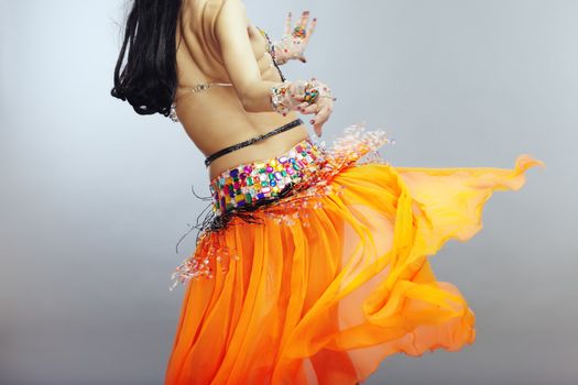 Backside of the belly dancer in traditional orange dress