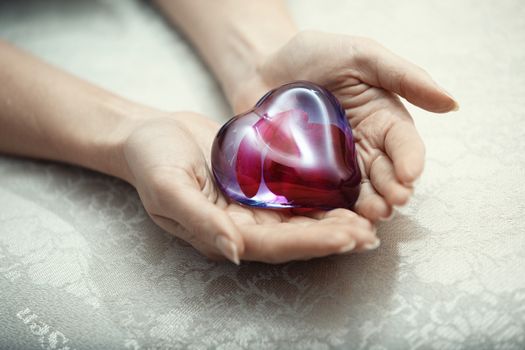 Woman hands holding heart shape object