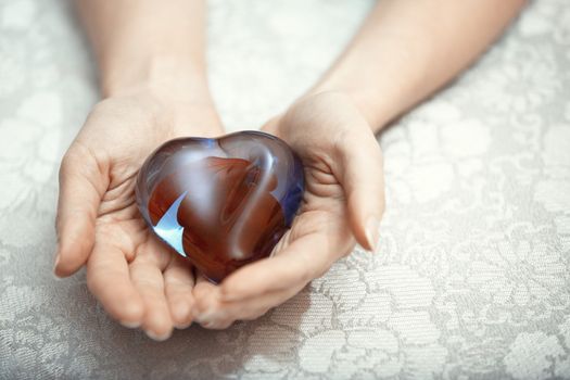 Woman hands holding heart shape object