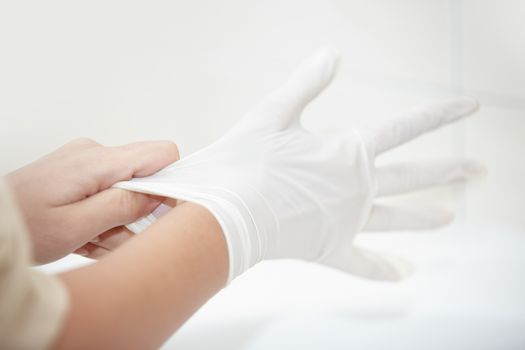 Hands of human taking on rubber gloves