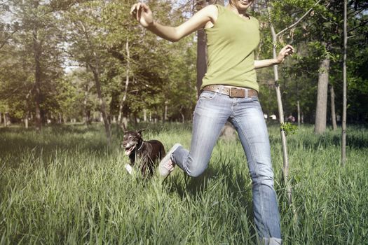 Happy girl outdoors running with her dog. Horizontal photo with daylight and natural colors