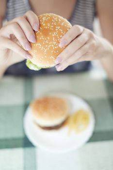 Woman holding humburger and sitting at the table