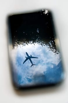 plane reflection on mobile phone with blue sky and tree