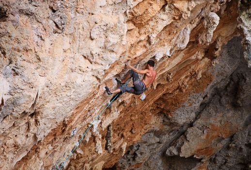 Male rock climber struggling his way up