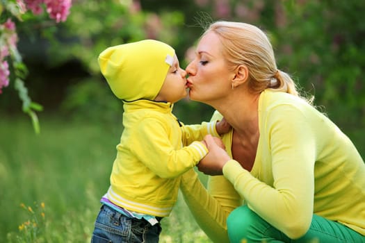 Little boy kissing his young mother outdoors