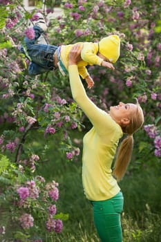 Happy young woman lifting her son high up
