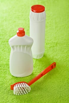 brush and white bottles on green background