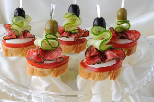 Canape of the baguette with salami on a glass base