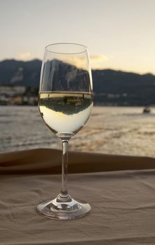 A glass of white wine with view of a lake