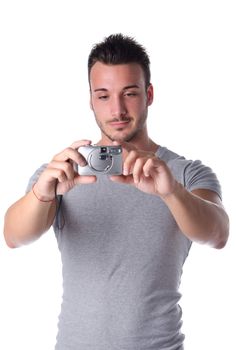 Attractive young man smiling and taking picture with compact photo camera