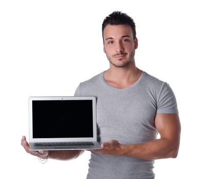 Attractive young man holding and showing laptop computer with blank screen, isolated on white