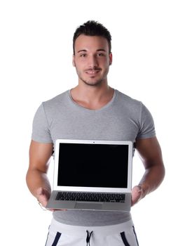 Attractive young man holding and showing laptop computer with blank screen, isolated on white