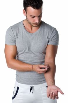 Muscular young man injecting medicine or taking blood from his arm with syringe