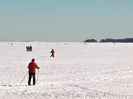 Person on skiis, at frozen waters, clear blue sky