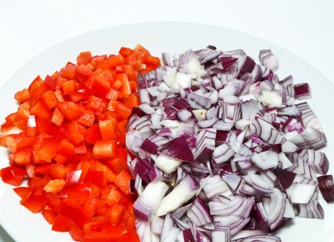 Chopped red onion and red pepper in a white ball, towards white background