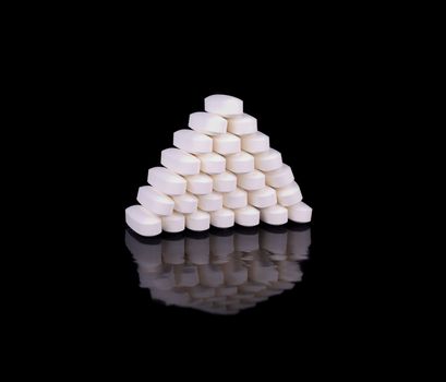 White pill l-arginine, stacked in a pyramid on a black background