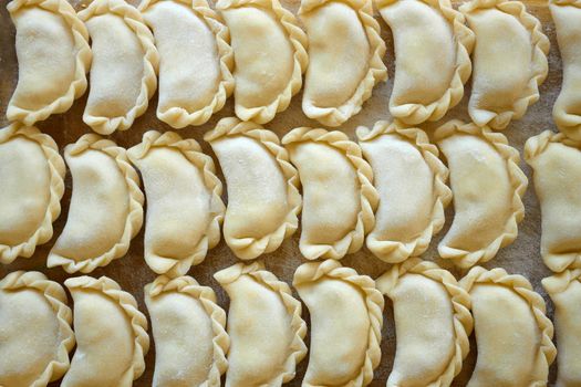 Dumplings with potatoes on the kitchen board. Dumplings with potatoes (or cottage cheese, cabbage, cherries, etc.) is a traditional Ukrainian and East Slavic kitchen dish is also known as Varenyky or Vareniks