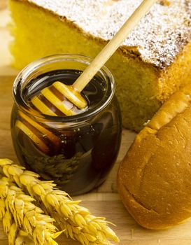 Healthy jar of honey with bakery products on wooden background.