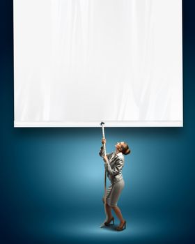 Image of young businesswoman pulling blank banner. Place for text
