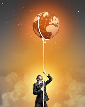 Image of businessman climbing rope attached to earth planet