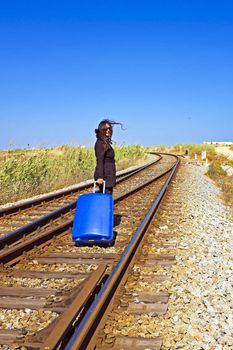 Young woman with her suitcase on a railroad track